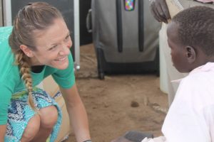 Amy Compston fits a shoe on the foot of a child during the Amy For Africa / Samaritan's Feet shoe distribution last week in Uganda. MARK MAYNARD / The Independent